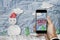 Smartphone on hand with `SALE` on screen, with crumpled paper cut snowman in winter, Christmas shopping sale