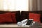 Smartphone, headphones and book stack on wooden table against defocused sofa with pillows. Front view