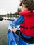 Smartphone image young boy in red life jacket kayaking from behind