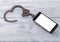 Smartphone, iron handcuffs on a wooden background.