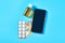 Smartphone near bottle with vaccine, pills and banknote of one hundred dollars on blue background
