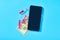 Smartphone near red vaccine and banknote of one hundred dollars on blue background