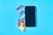 Smartphone near red vaccine, syringe and banknote of one hundred dollars on blue background