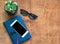 Smartphone with red earphones, blue notebook and black eyeglasses on wooden background. View from above