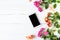 Smartphone, roses on the table. Women`s things Fashion womens desk Top view Mockup