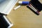 A smartphone, two different color pens, and a pile of books are placed on a wooden table.