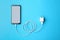 Smartphone and USB charger on blue background, flat lay. Modern technology