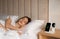 Smartphone, watch, earphones charging on wireless pad and sleeping woman