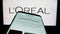Smartphone with webpage of French personal care company L\\\'Oreal S.A. on screen in front of business logo.
