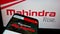 Smartphone with website of Indian automotive company Mahindra Mahindra Limited on screen in front of logo.