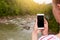 Smartphone in woman`s hand, photographer makes photo of beautiful nature, blank screen on device. Photo of mountain river and