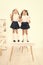 Smarty girls. Little school girls standing on desk in classroom. Small girls with long hair tails wearing fashion school