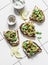 Smashed grilled eggplant bruschetta with yogurt herbs sauce - delicious appetizers, snacks, tapas on light background, top view