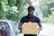 Smile african male postal delivery courier man in front of car delivering package