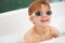 Smile, bath and a boy in swimming goggles having fun while cleaning for natural hygiene in water. Children, soap and