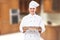 Smile male chef standing in kitchen and hold wooden board mock up with food meal