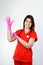 Smile medic female in red form pulls on her hands rubber gloves, Ambulance
