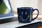 Smile pattern on blue ceramic coffee cup on laptop