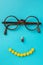 Smile from pills, glasses, blue background. Black Eye Glasses with white pills on blue background