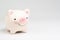 Smile pink piggy bank on white background with copy space using as happy saving and investment or positive economic and finance