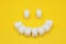 Smile symbol, composed of cubes of sugar on yellow background. Concept of sugar leading to caries