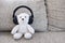 Smile white teddy bear sitting on sofa and wearing headphone