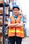 Smile woman worker crossed arm and standing in the warehouse distribution center. Engineer wears a safety helmet and vest. In