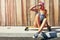 Smile because you can. a young woman sitting on her skateboard on a sidewalk.