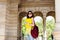 Smiled brunette girl in sunglasses is posing to camera with yellow laptop on archway background. She wears vinous bag