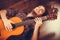 Smiled male with wooden guitar.