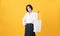 Smiley Asian woman in casual white t-shirt stand and holding bag canvas fabric for mockup logo on the yellow background.