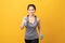 Smiley Asian woman wearing sportswear pumping up muscles with blue dumbbell on light orange background. Healthy lifestyle concept.