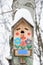 Smiley birdhouse. Birdhouse in the form of a funny face on the tree. Handmade wooden nesting box covered in snow. Winter landscape