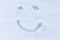 Smiley drawing in the snow. Woman in the fresh, untouched snow. Graza and smile, emoji