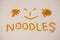 Smiley face and noodles text made out of pennette pasta