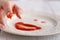 Smiley face of tomato source on white plate over wooden background