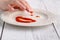 Smiley face of tomato source on white plate over wooden background