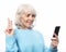 Smiley senior woman is holding a new smartphone in her hand.