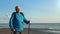 Smiling active elderly man Scandinavian walking stick cardio sport exercise at sunny sand sea beach