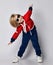Smiling active frolic blond kid boy in blue and red hoodie, pants and sunglasses does gym exercises