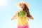 Smiling active woman showing watermelon against blue sky