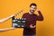 Smiling actor performing while second assistant camera holding clapperboard on orange background