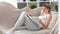 Smiling adorable domestic woman reading book lying on couch at living room full shot