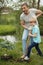 Smiling adult father and his son planting a tree outdoors in park.