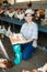 Smiling adult latin woman in plaid shirt and cap collecting eggs in chicken farm