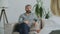 Smiling adult man sitting on couch and talking to female psychoanalyst in her office indoors