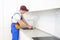 smiling adult repairman with spanner repairing faucet at kitchen