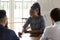 Smiling african American female employee interact with colleagues at meeting