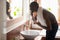 Smiling african american guy bending over sink with running water.