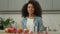 Smiling African American happy woman ethnic girl biracial lady female smile at camera at home kitchen with fruits apples